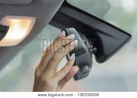 the girl in the car with beautiful manicure adjusts the rearview mirror