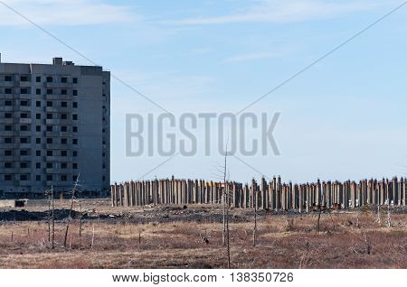 The unfinished high-rise building and a pile field, the Arctic tundra, Norilsk. House on pile foundation, built on permafrost.