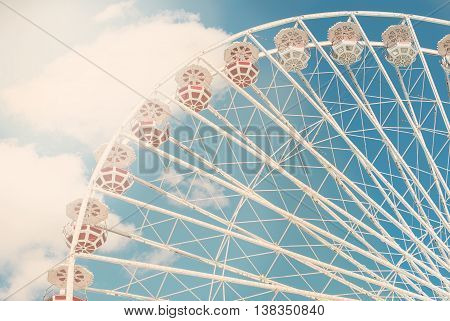 Attraction Ferris wheel against the blue sky with a few clouds on a sunny day