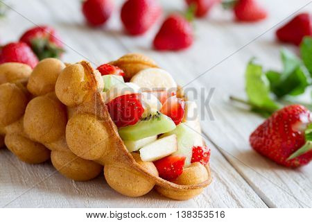 waffles with fruits strawberries apple and kiwi on the wooden table