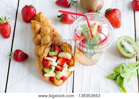 waffles with fruits strawberries apple and kiwi and lemonade on the wooden table