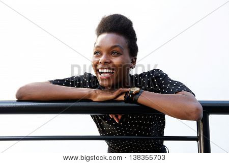 Young African Woman Leaning On Railing And Laughing