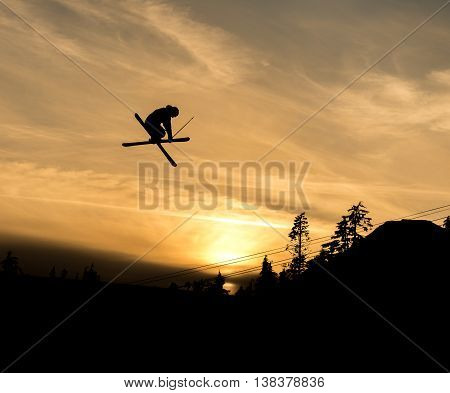 silhouette of skier doing grab off a jump in the sunset
