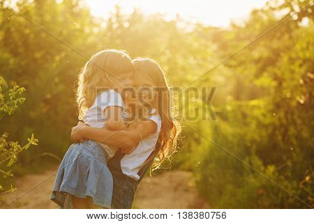 Two little sisters hugged strongly in park on a sunny summer day. Family time. Cute babies.
