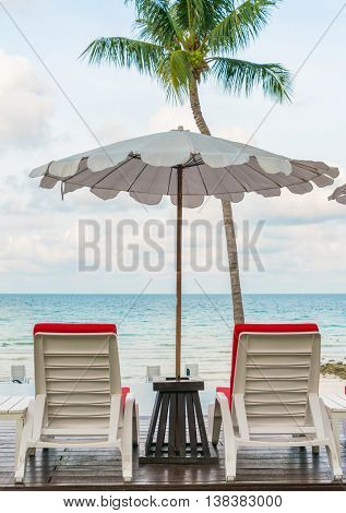 Beautiful beach chairs with umbrella around outdoor swimming pool neary sand and sea