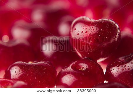 Cherry background with cherry in form of heart. Ripe fresh rich cherries with drops of water. Macro. Texture. Fruit background. Valentine's Day.