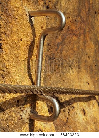 Detail of steel anchor eye and rope end anchored into sandstone rock. Iron twisted rope fixed in block by screws snap hooks.  Trekking via ferrta.