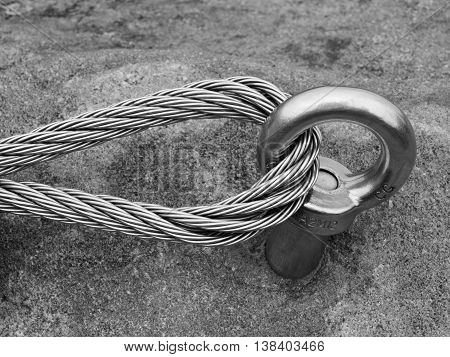 Detail of steel anchor eye and rope end anchored into sandstone rock. Iron twisted rope fixed in block by screws snap hooks.