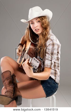 Sesy vaquera en el sombrero de vaquero con guitarra acústica