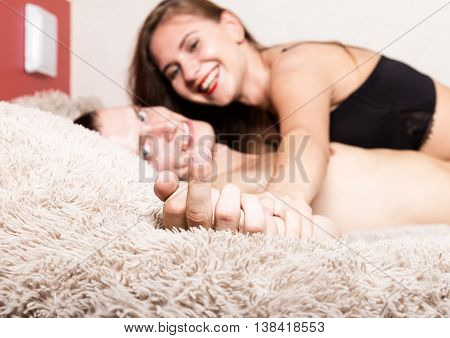 Sexy young couple kissing and playing in bed. close-up of hands and bulging middle finger.
