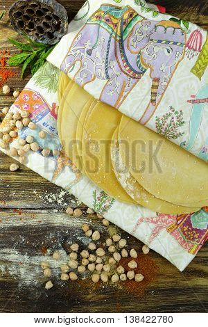 Colorful Indian food - papadum chickpea gram flour and spices on textured wooden table top