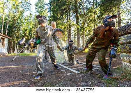 Two players rescue their friend from coming locomotive in paintball game