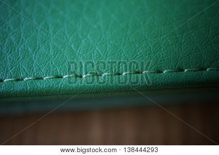 Macro detail of a green thread stitching green stitched leather case