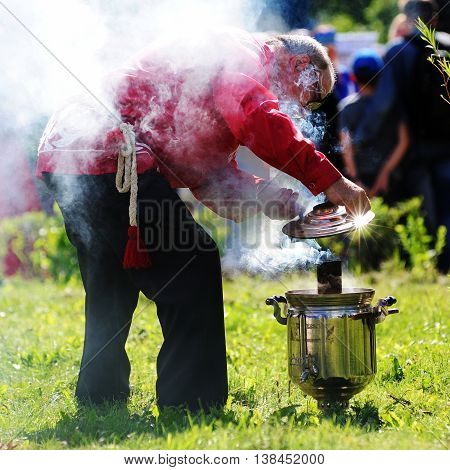 Orel Russia - July 08 2016: Russian Valentine Day - Petr and Fevronia. Man in Russian suit lighting samovar closeup