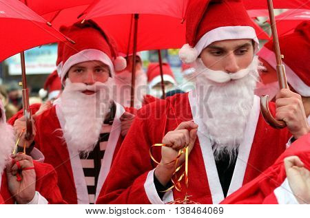 Uzhgorod Ukraine - December 19. 2008: Young people under the red umbrellas dressed as Santas are marshing the city's streets during the Parade of Santa Clauses.