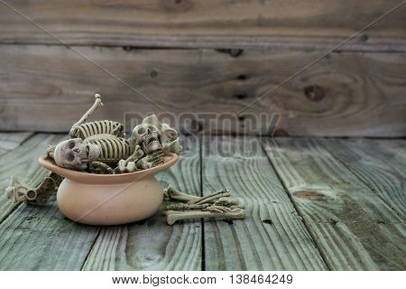 Skull skeleton in clay pot on old wood background