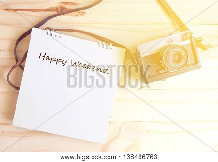 retro camera and notepad writing happy weenkend with sunlight on wooden backgroundhappy weekend concept