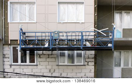 construction suspended blue cradle without workers on a newly built high-rise building