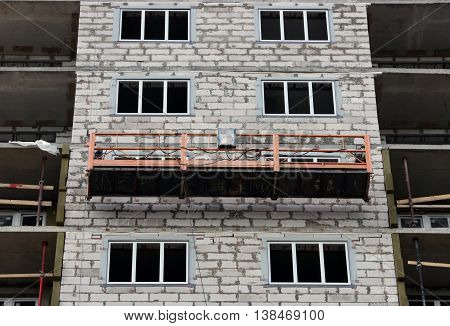 construction suspended orange cradle without workers on a newly built high-rise building