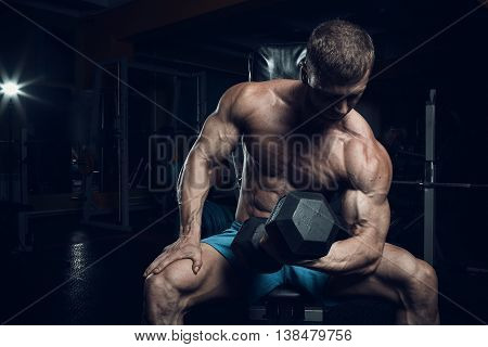 Male bodybuilder fitness model trains in the gym