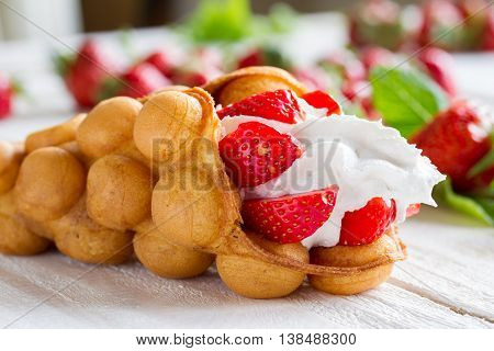 waffles with strawberries and whipped cream on the wooden table