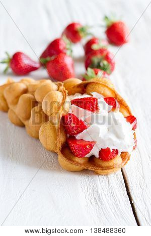 waffles with strawberries and whipped cream on the wooden table