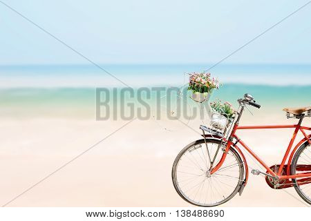 Old red Bicycle with basket flowers on blured beach tropical sea background