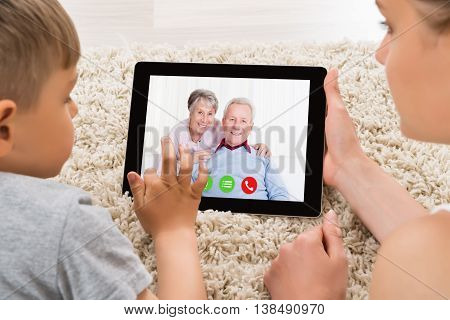 Close-up Of Mother And Son Videoconferencing On Digital Tablet At Home