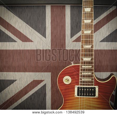 British Rock Invasion concept - detail close up of a guitar leaning against an amplifier with British Union Jack flag on the cabinet on stage at a concert - vintage toned Instagram style