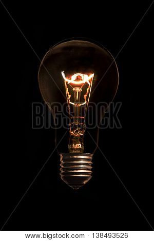 Glowing light bulb without wires on black background.