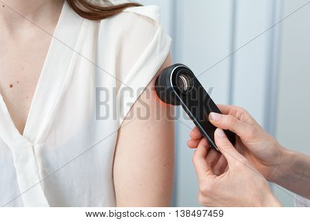Doctor examining birthmarks and moles on a female patient (examination of birthmarks)