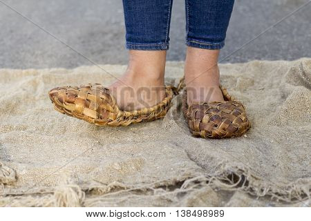 Feet girl in old Russian bast shoes are on canvas, which lies on the road.