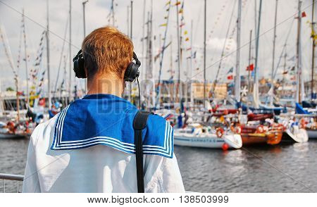 Young Sailor in headphones on the Shore Looking at the Boats