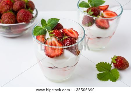 Fresh strawberries dessert layered with yogurt on white background. Diet yogurt dessert with ripe strawberry.