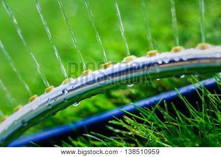 Lawn sprinkler spaying water over green grass. Motion blur. Select focus.