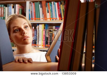 ภาพของนักเรียนที่ฉลาดหาหนังสือในห้องสมุดวิทยาลัย