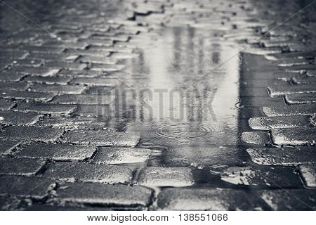 Rainy day. Reflection of the building in puddle on the city street during rain.