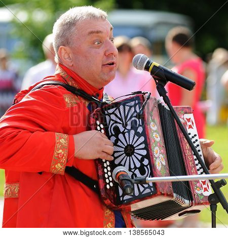Orel Russia - July 08 2016: Russian Valentine Day - Petr and Fevronia. Senior man in red outfit playing garmoshka Russian accordion closeup