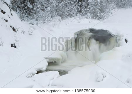 Kivach falls. The frozen river in the winter wood. Karelia. Russia. Winter landscape.