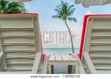 Beautiful beach chairs with umbrella around outdoor swimming pool neary sand and sea