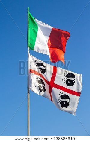The Italian national flag and that of the region of Sardinia with the four Moors waving together in the blue sky
