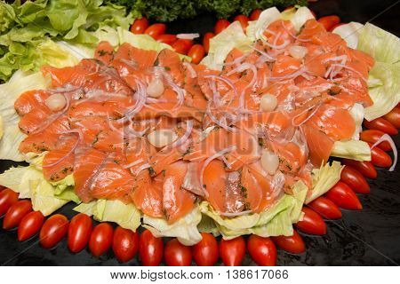 Slices of salmon gravlax on a black dish.