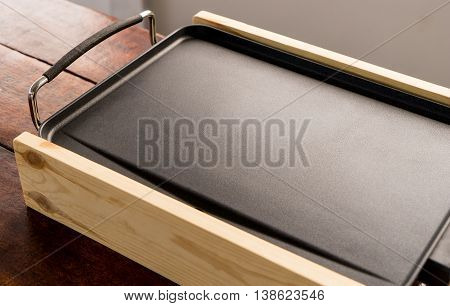 Empty Electrical cooking pan on wooden table. Small portable cooking pan with copy space.