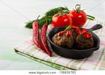 Grilled meatballs served with chili pepper slices in cast iron skillet. Grilled bbq meatloaf. Barbecue Meatballs.