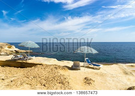 Sun loungers on a beach underneath a parasol overlooking the Mediterranean sea