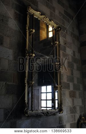 antique mirror in a gilt frame on the stone wall