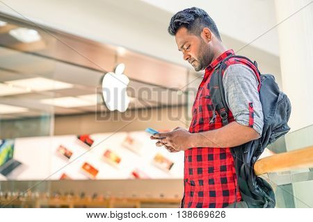 RIMINI ITALY - JUNE 24 2016: Man using smartphone in front of Apple store located in a shopping center on Via Caduti di Nassiriya Rimini ITALY