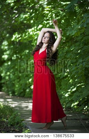 Beautiful young caucasian brunette woman in red dress outdoors whole-length portrait