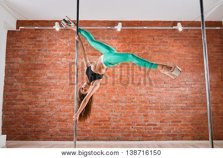 Young sexy pole dance woman doing acrobatic tricks with pylon.
