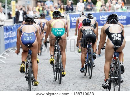 STOCKHOLM - JUL 02 2016: Rear view of colorful group of triathlete cyclists Zaferes Van Coevorden Ueda Ide and audience in the Women's ITU World Triathlon series event July 02 2016 in Stockholm Sweden